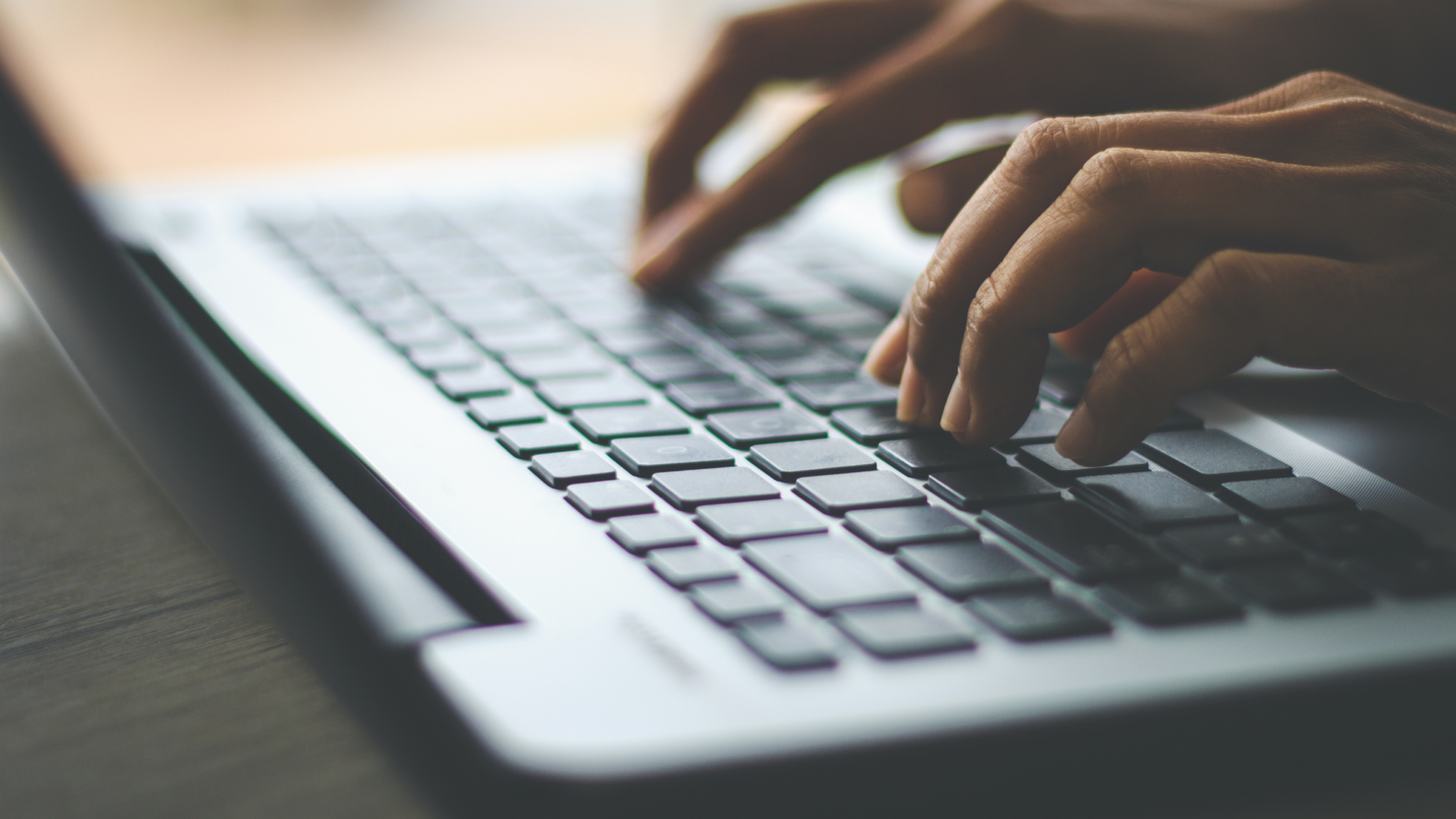 Hands type on a laptop keyboard